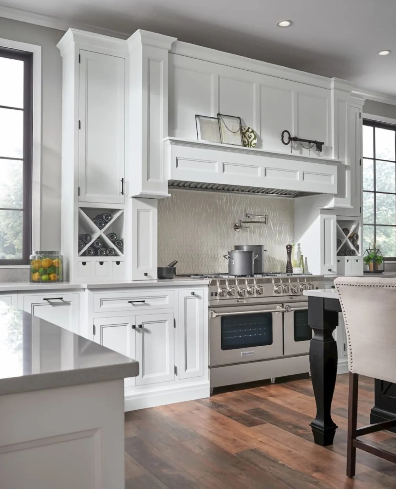 Painted kitchen cabinetry with a custom hood surround and built-in wine storage